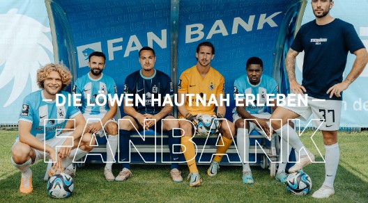 Mehrere Spieler des TSV 1860 auf einer Bank am Spielfeldrand mit Schriftzug "Fanbank"