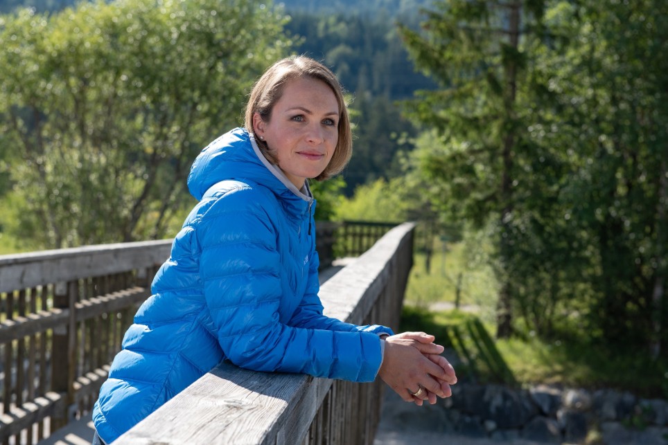 Magdalena Neuer steht auf einer Holzbrücke im Grünen und schaut in die Ferne.