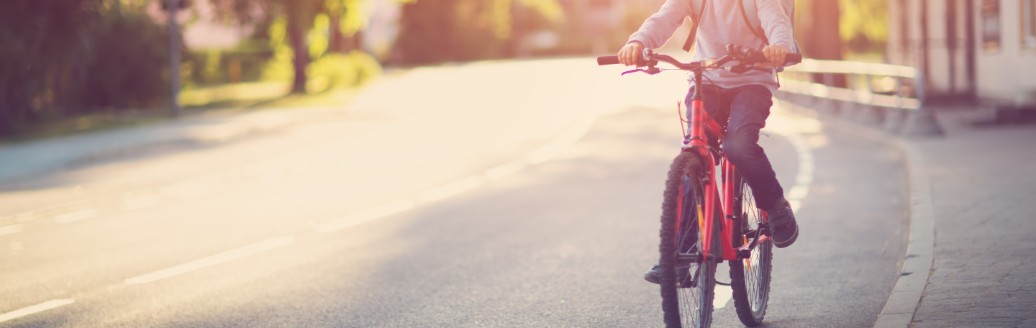 Ein junges Kind fährt mit seinem Fahrrad den Fahrradstreifen auf einer Straße entlang. 