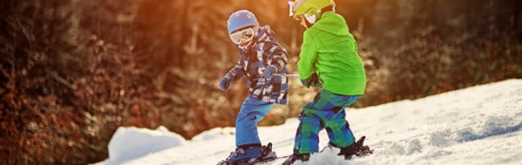 Zwei kleine Kinder mit ihren Skiern auf der Skipiste.