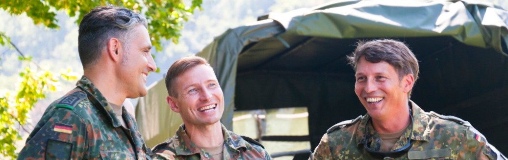 Drei junge, männliche Bundeswehr-Soldaten unterhalten sich lachend. Sie tragen alle Uniform. 