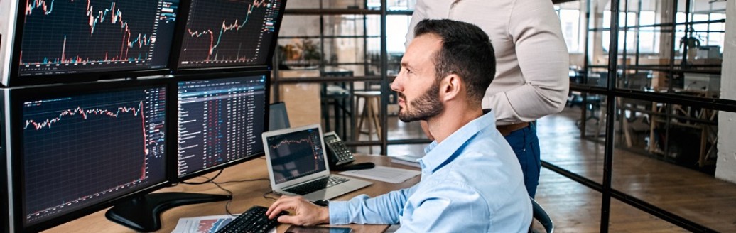 Zwei Männer sind im Büro und schauen zusammen auf einen Computerbildschirm.
