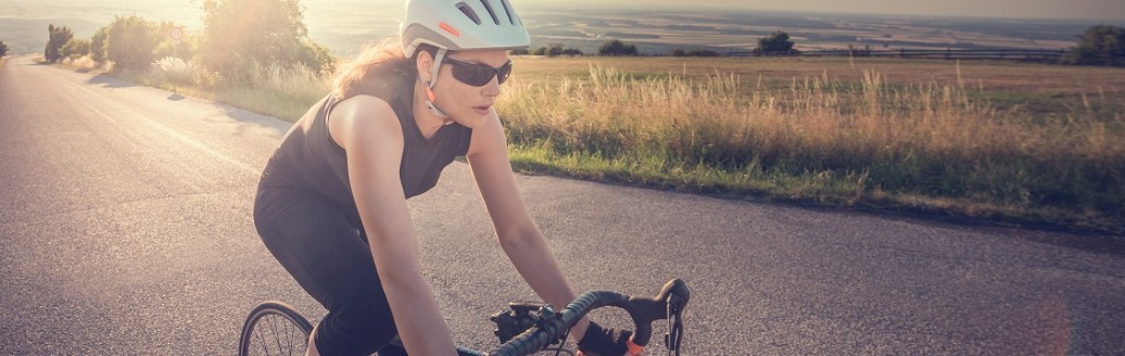 Eine junge Frau fährt eine Landstraße entlang auf ihrem Rennrad.