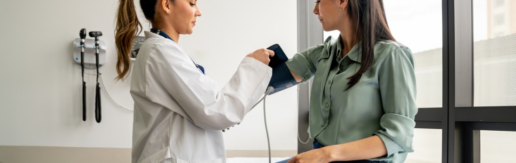 Ärztin misst einer Patientin den Blutdruck in einem Behandlungsraum.