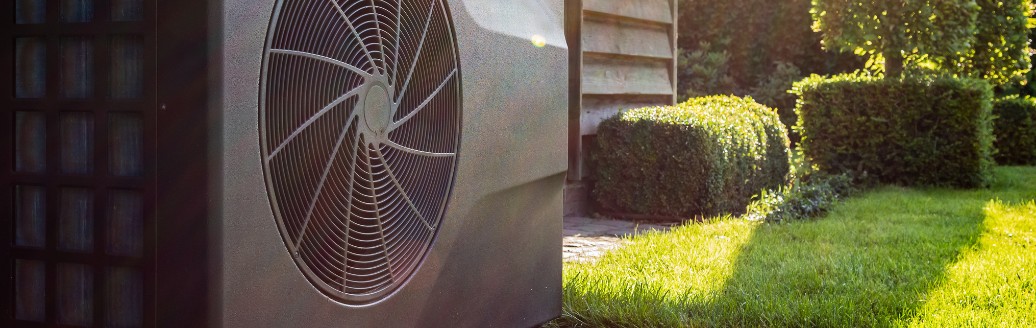 Eine im Garten stehende Wärmepumpe bei Sonnenlicht.