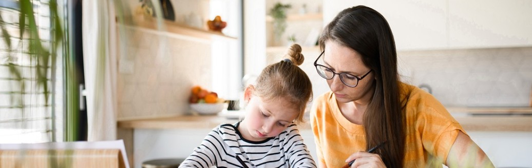 Eine Frau macht mit ihrer Tochter gemeinsam Schulaufgaben. 