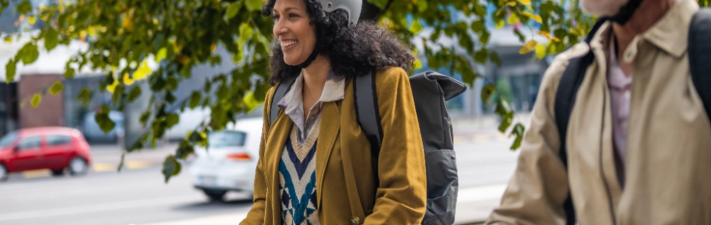 Älterer Mann fährt neben einer jüngeren Frau geschützt mit Helm E-Scooter.