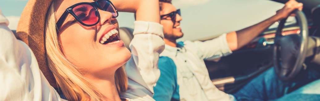 Eine Frau und  ein Mann sitzen zusammen im Cabrio und genießen das sonnige Wetter. 
