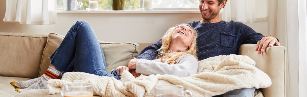 Ein Mann und eine Frau sitzen entspannt zuhause auf ihrem Sofa