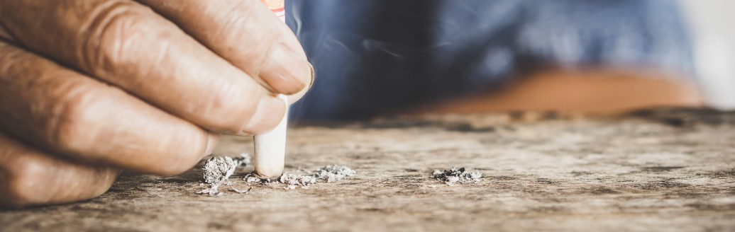 Eine zusehende, etwas verschmutzte Hand drückt eine Zigarette aus.