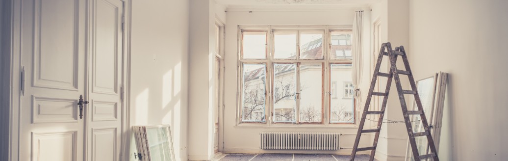 Das Bild zeigt einen leerstehenden, weißen Altbau-Raum, der gerade renoviert wird. 