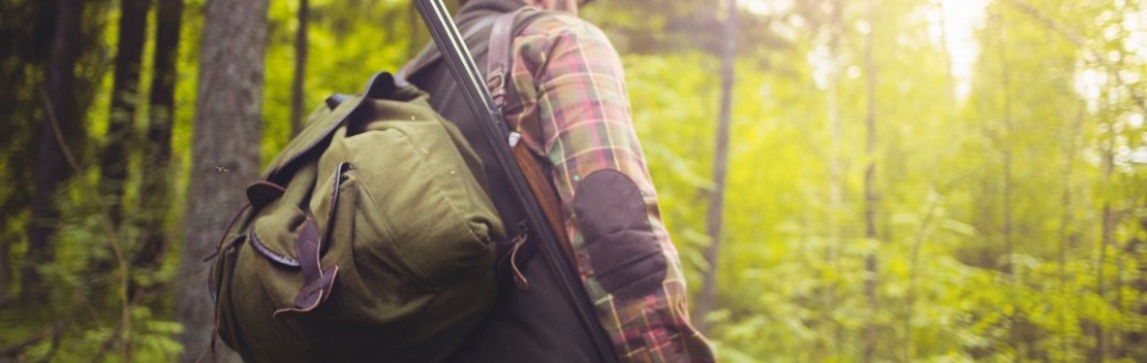 Ein von hinten fotografierter Jäger, der im Wald unterwegs ist.