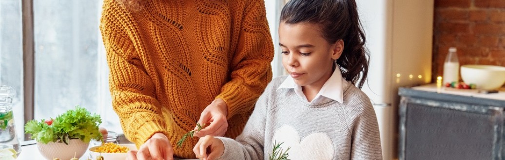Eine Mutter macht  mit ihrer Tochter einen Auflauf in der Küche zusammen. 