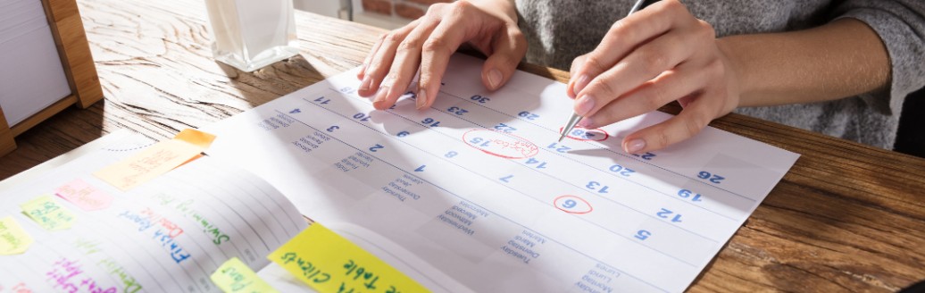 Eine Frau plant mit einem ausgedruckten Kalender ihren Urlaub. 