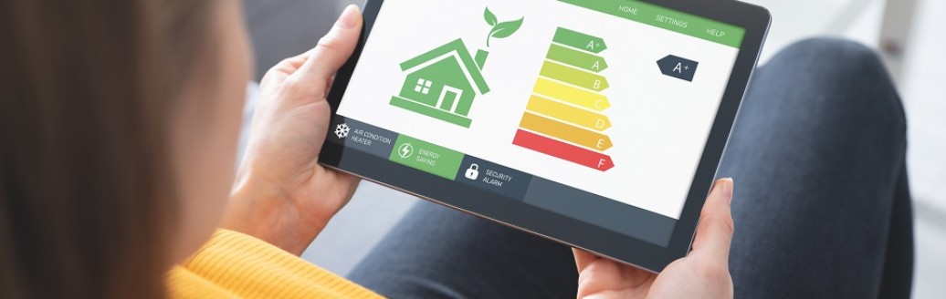 Eine Frau sitzt auf dem Sofa und schaut sich die Energieeffizienzklassen auf dem Tablet an.