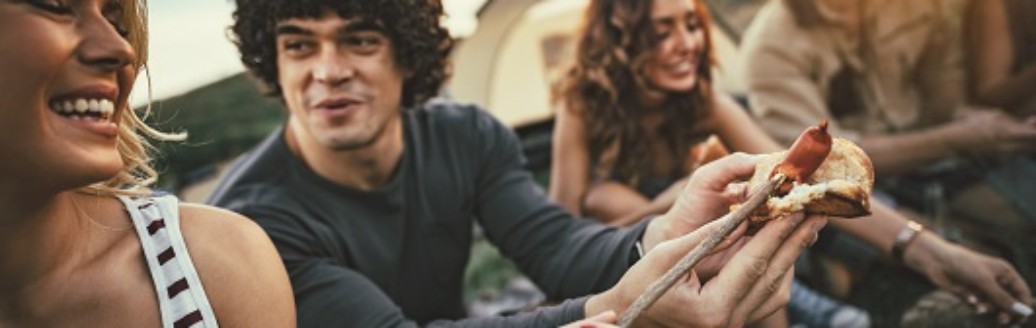 Mehrere Freunde sitzen zusammen und grillen