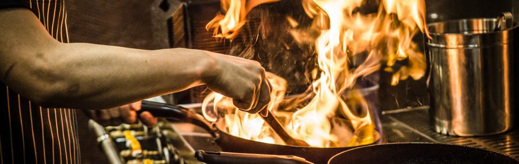 In einer professionellen Küche kocht ein Koch mit Feuer