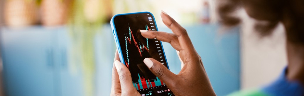 Frau zoomt mit den Fingern näher an eine Aktien-Grafik auf ihrem Handy.
