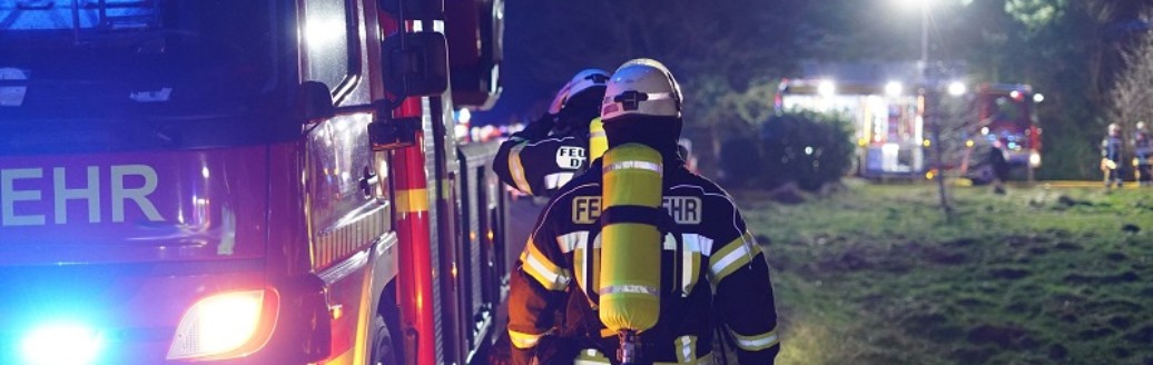 Feuerwehrmänner gehen entlang Feuerwehrauto zum Einsatz abends.