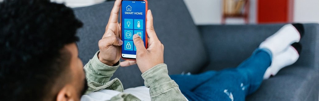 Ein Jugendlicher liegt auf dem Sofa und hält sein Mobiltelefon in der Hand. 