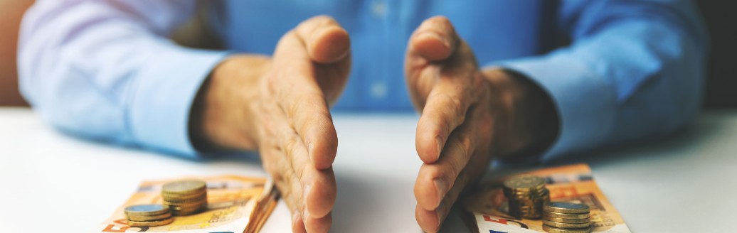 Eine junge Frau sitzt am Tisch und notiert etwas. Auf Tisch steht ein Sparschwein.