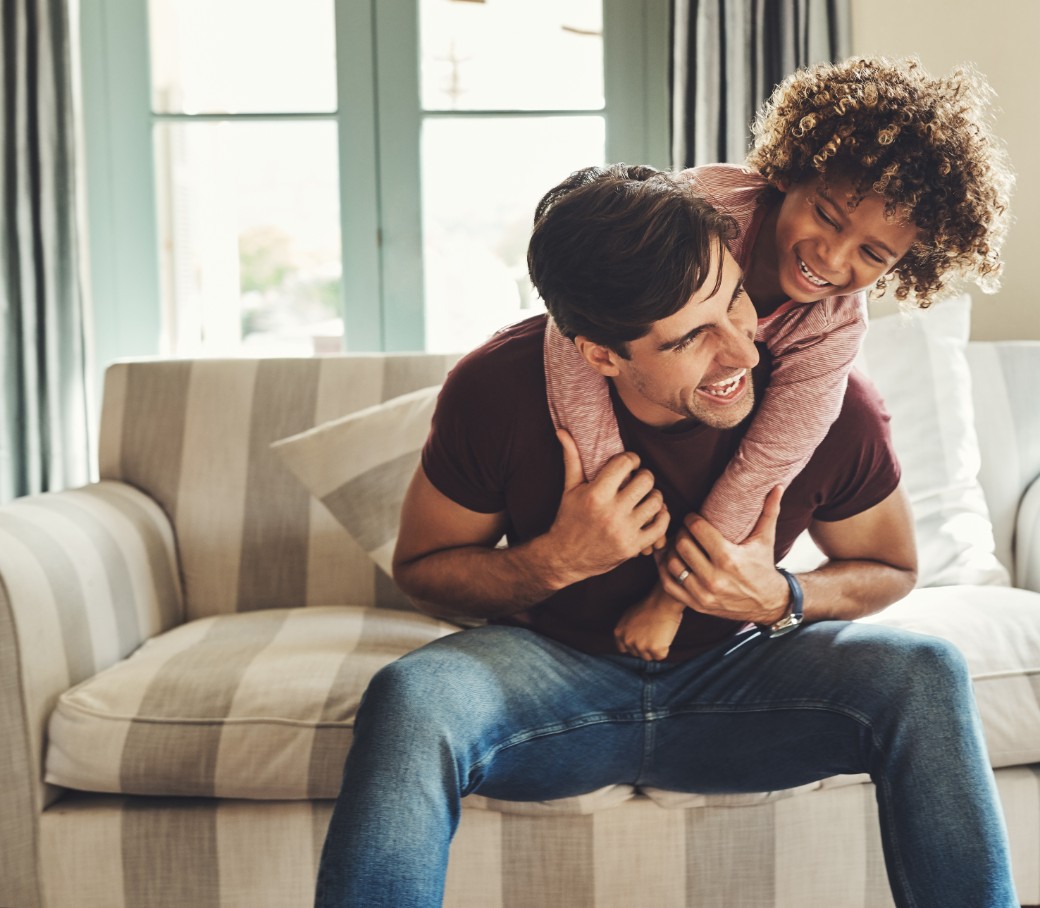 Vater und Kind tollen zuhause auf dem Sofa