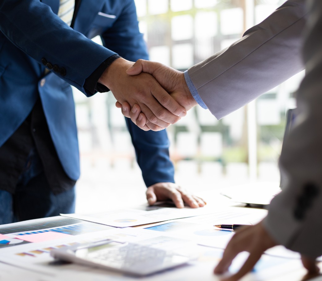 Zwei Menschen geben sich über einen Schreibtisch hinweg die Hand