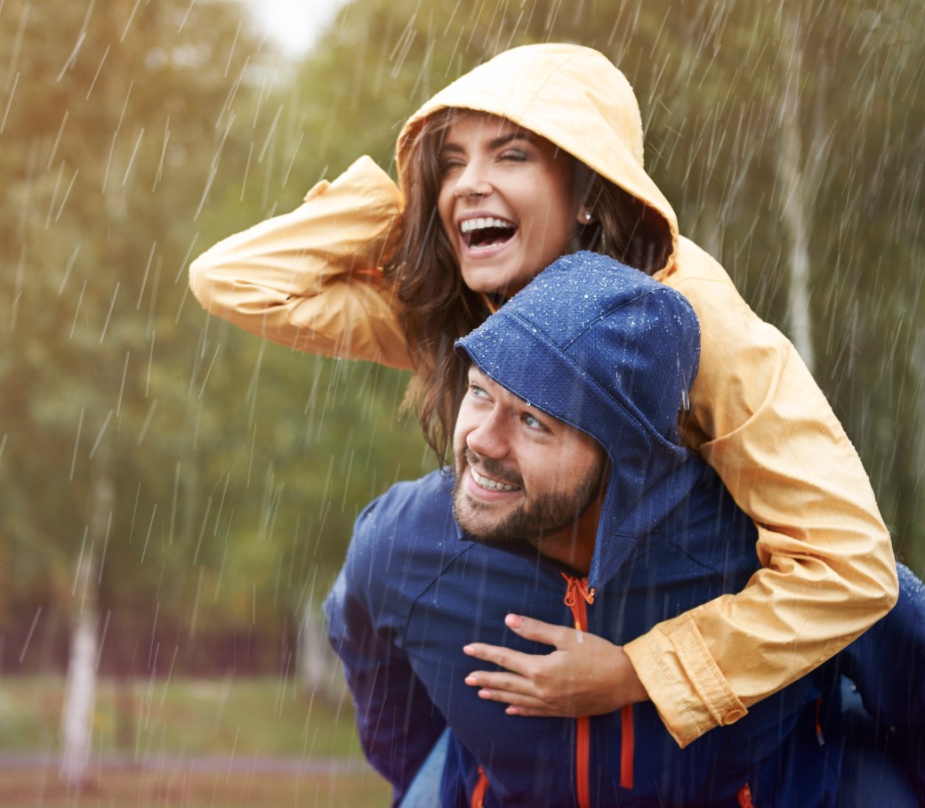 Ein Mann und eine Frau laufen lachend durch den Regen