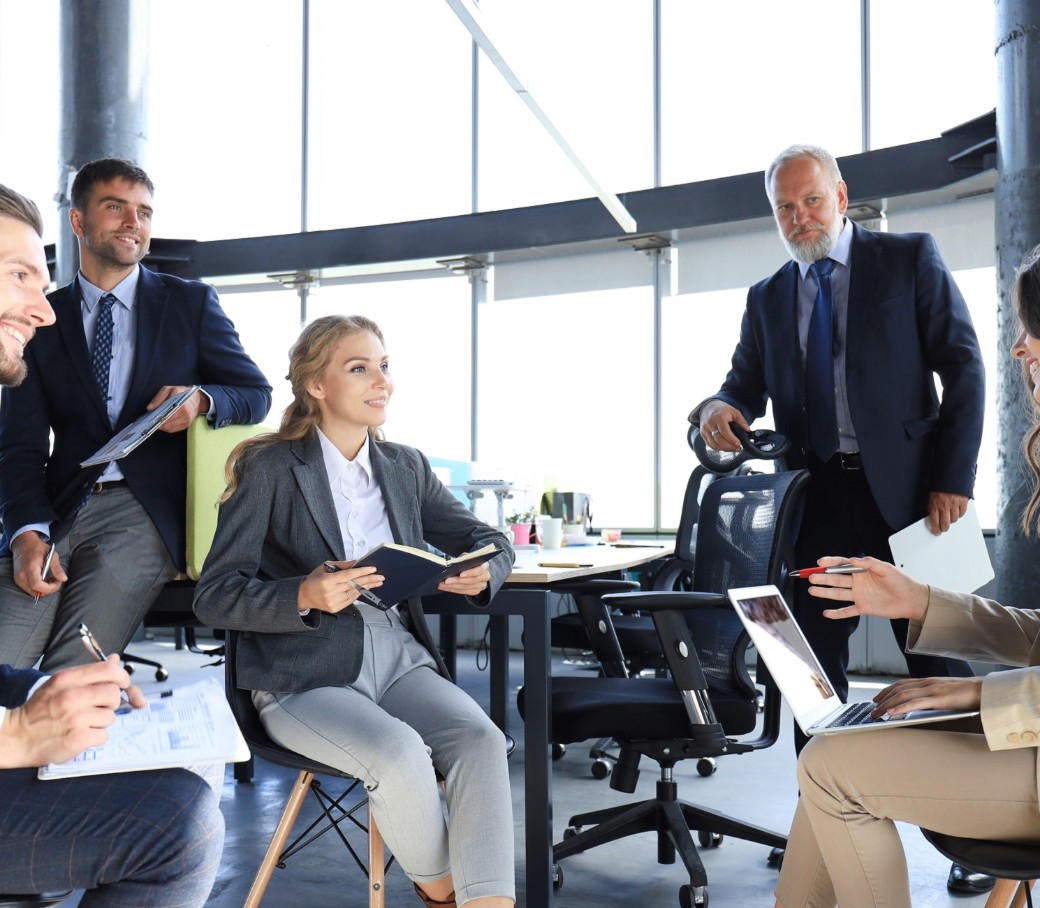 Fünfköpfiges Team bespricht sich in einem hellem Bürogebäude