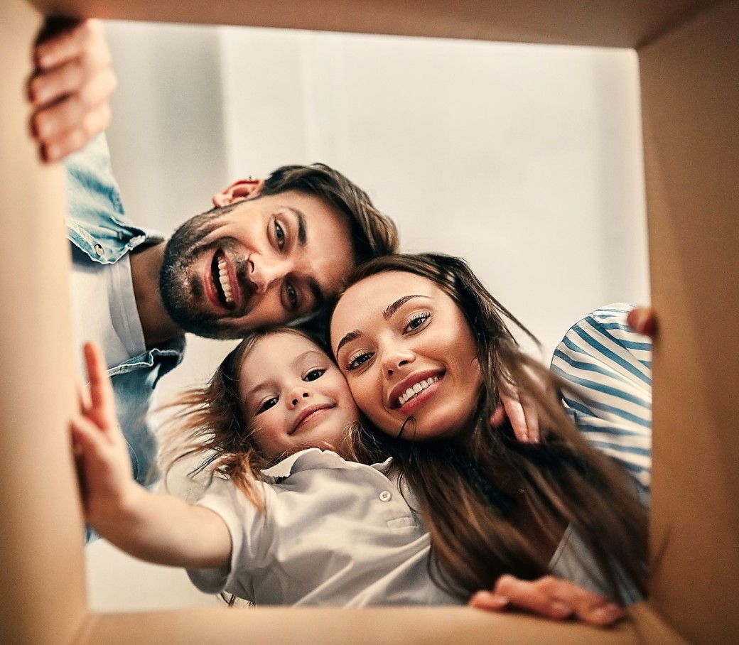 Eine lachende Familie sieht von oben in einen Karton