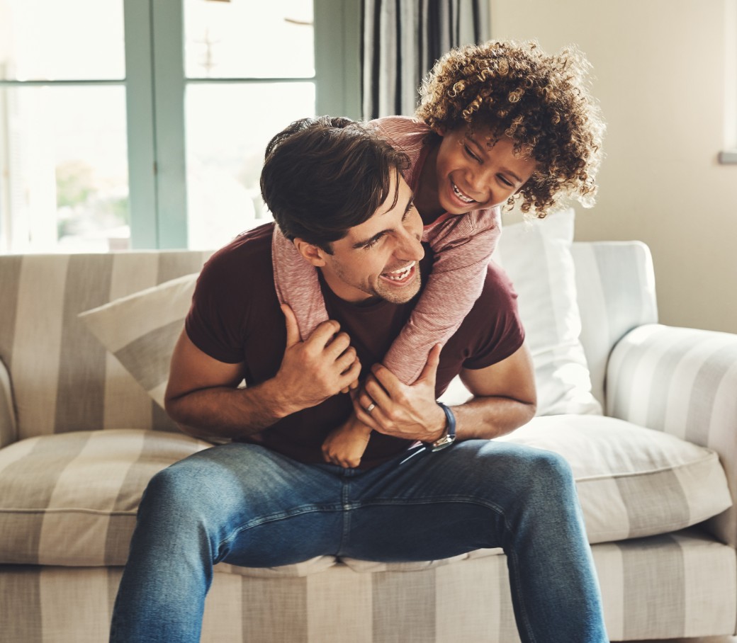 Vater und Kind tollen zuhause auf dem Sofa