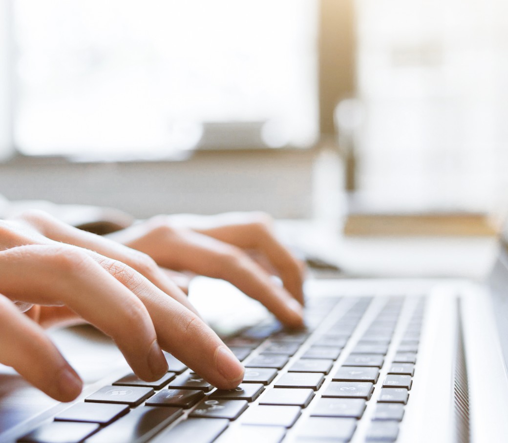 Hände tippen auf einer Laptop-Tastatur