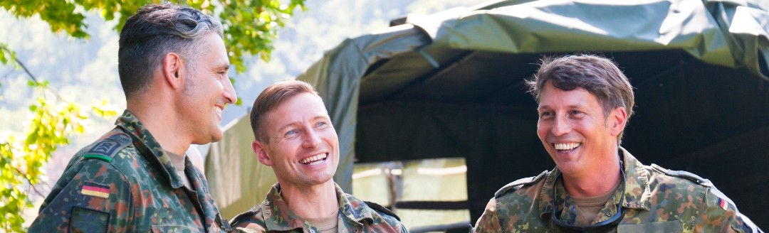 Drei junge, männliche Bundeswehr-Soldaten unterhalten sich lachend. Sie tragen alle Uniform. 