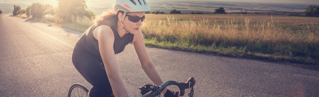 Eine junge Frau fährt eine Landstraße entlang auf ihrem Rennrad.