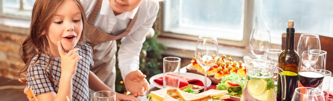 Eine ältere Dame und ein junges Mädchen stehen gemeinsam an einem Weihnachtsbuffet.