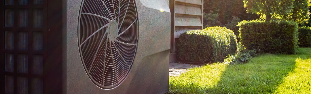 Eine im Garten stehende Wärmepumpe bei Sonnenlicht.