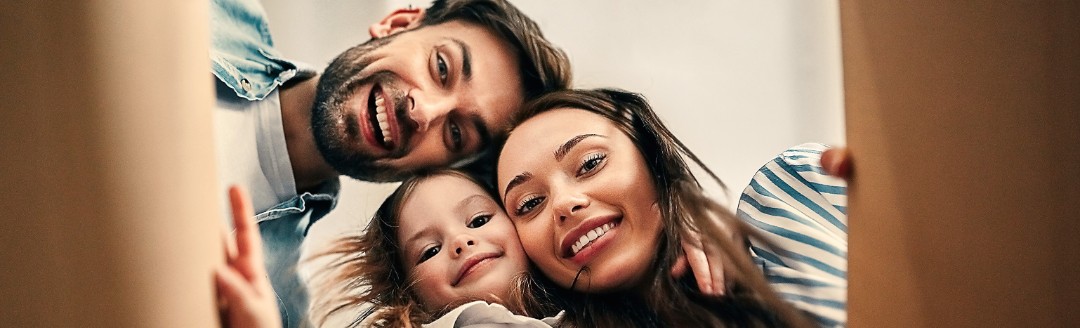Eine lachende Familie sieht von oben in einen Karton