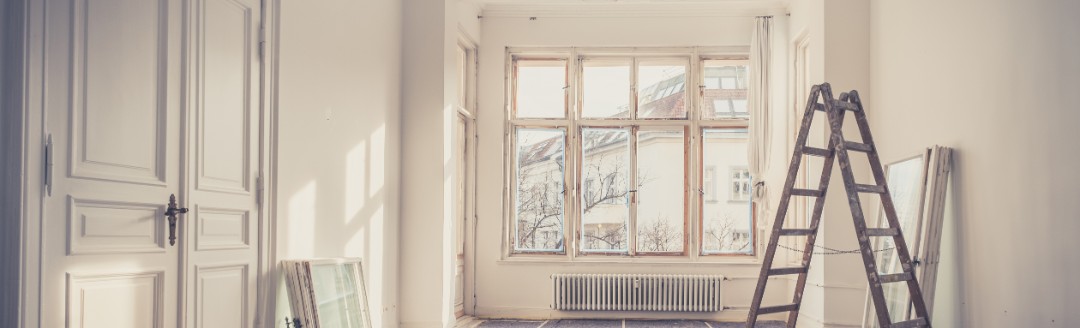 Das Bild zeigt einen leerstehenden, weißen Altbau-Raum, der gerade renoviert wird. 
