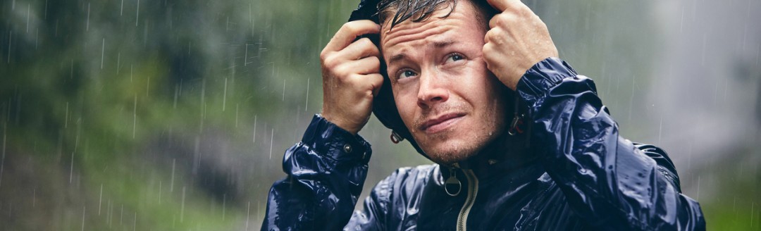Ein Mann hat seine Kapuze auf, um sich vor dem starken Regen zu schützen.