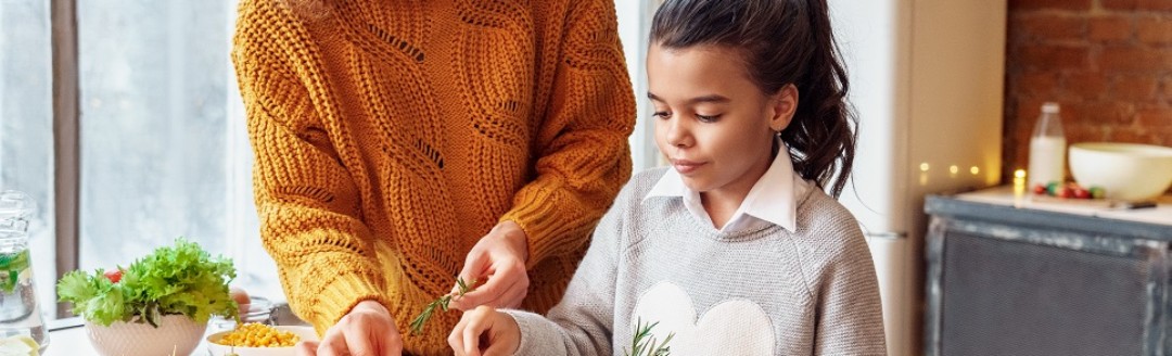 Eine Mutter macht  mit ihrer Tochter einen Auflauf in der Küche zusammen. 