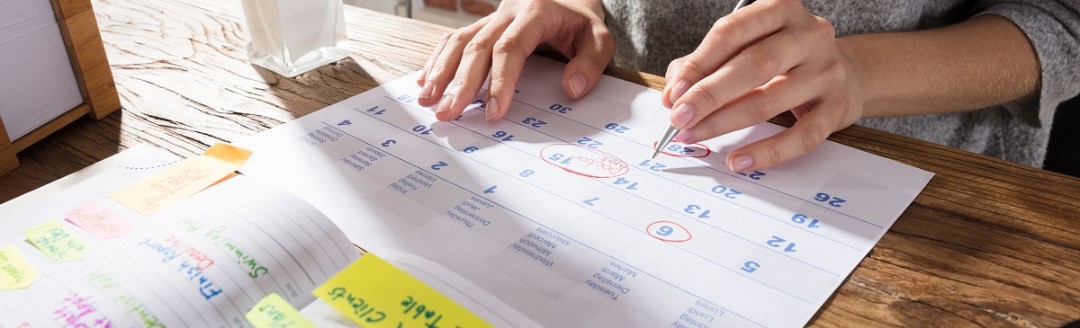 Eine Frau plant mit einem ausgedruckten Kalender ihren Urlaub. 