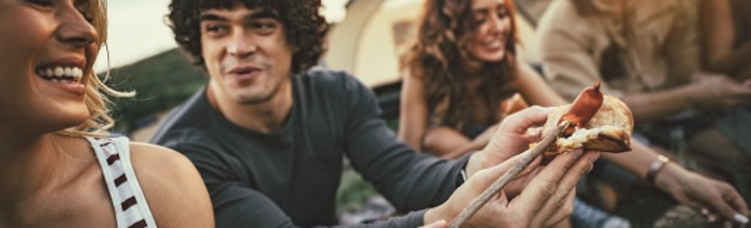 Mehrere Freunde sitzen zusammen und grillen