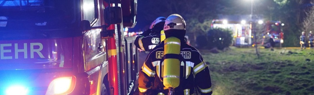 Feuerwehrmänner gehen entlang Feuerwehrauto zum Einsatz abends.