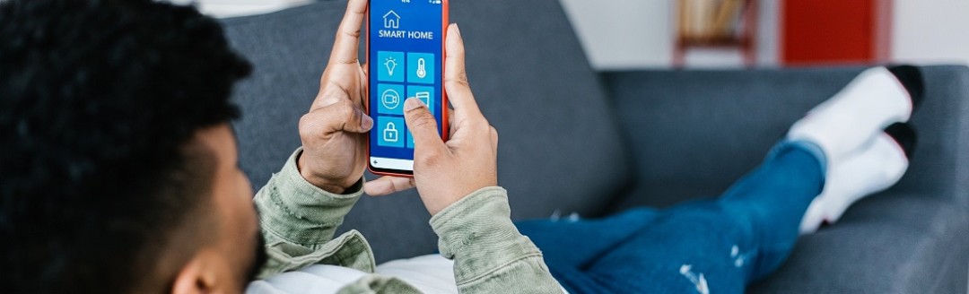 Ein Jugendlicher liegt auf dem Sofa und hält sein Mobiltelefon in der Hand. 