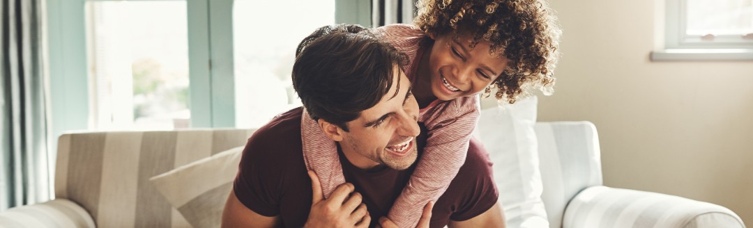 Vater und Kind tollen zuhause auf dem Sofa