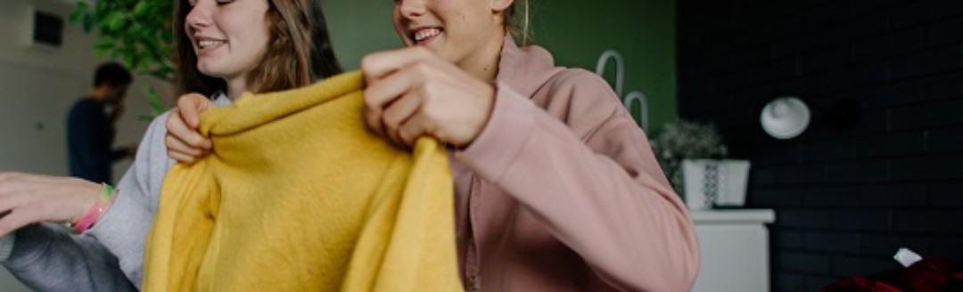 Zwei junge Frauen schauen sich gemeinsam Klamotten an.
