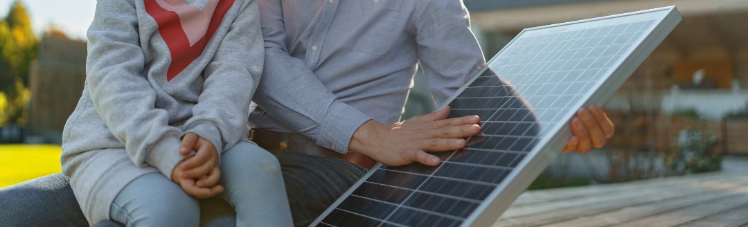 Vater zeigt seiner kleinen Tochter ein Solarpaneel für eine Photovoltaik-Anlage