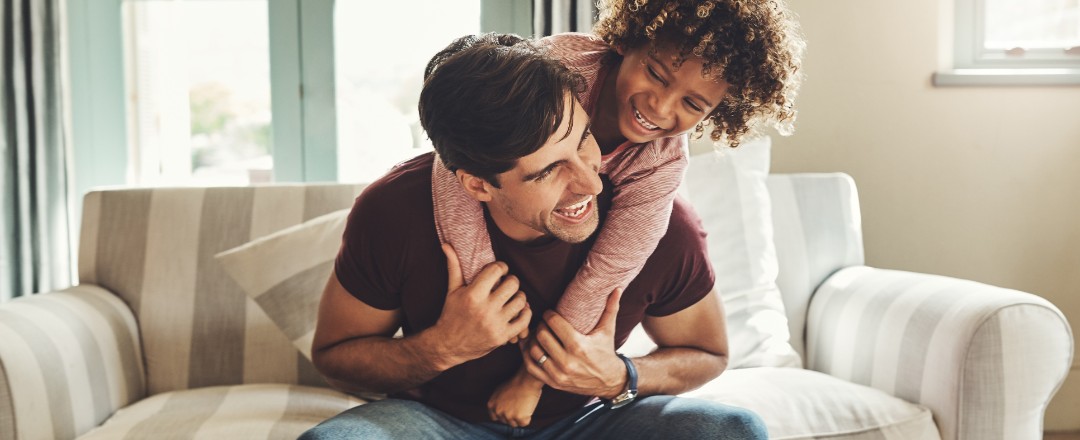 Vater und Kind tollen zuhause auf dem Sofa