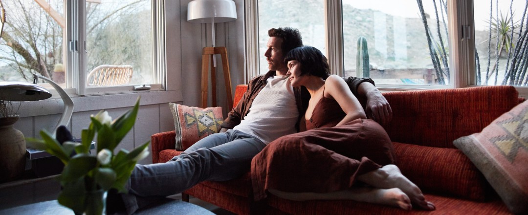 Ein Mann und eine Frau kuscheln sich auf dem Sofa aneinander.
