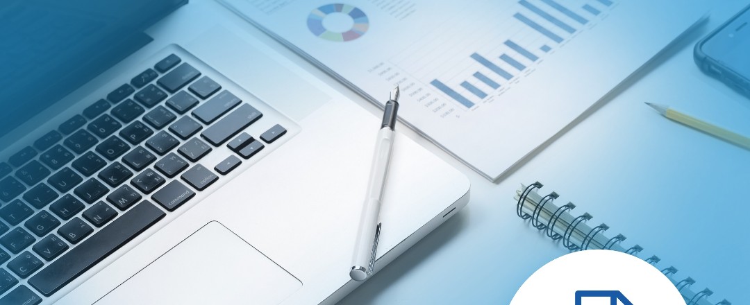 In blau gehaltenes Bild eines aufgeklappten Laptops, daneben ein Notizblock und Unterlagen